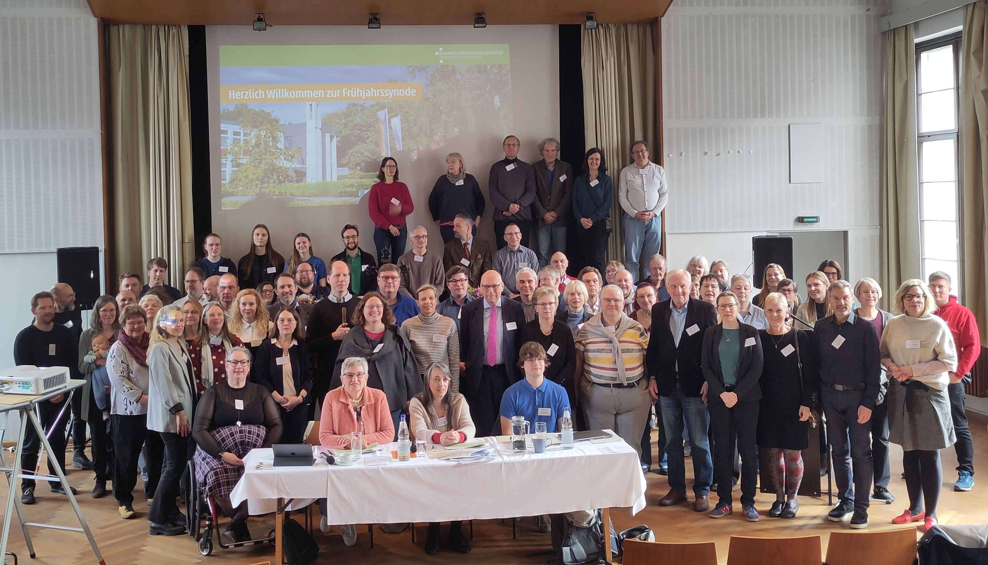 Viele Menschen postieren sich in einem Saal für das Foto.