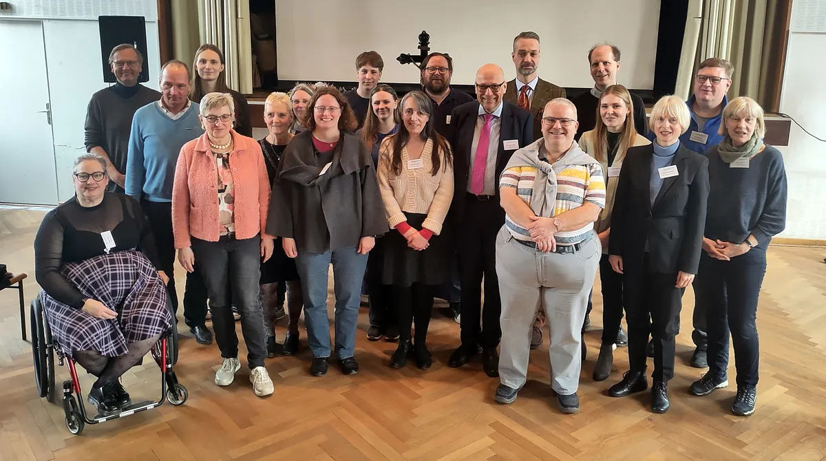 Menschen (Kreiskirchenratsmitglieder) stehen in einem Saal